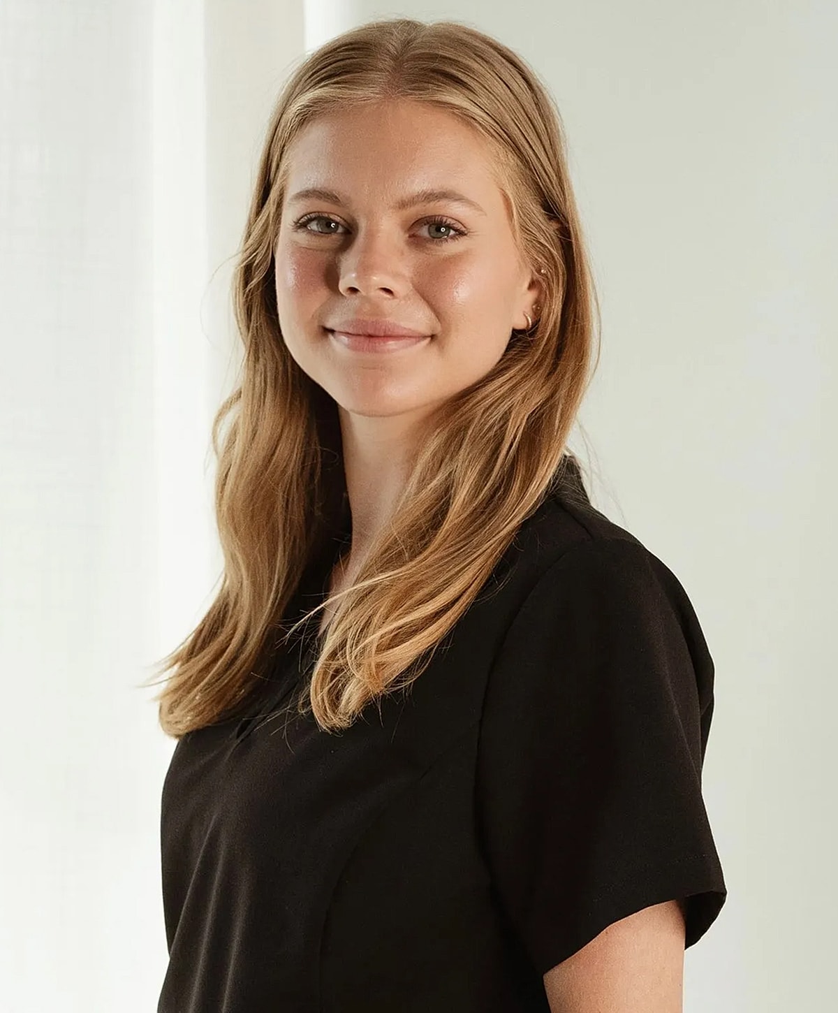 Young woman smiling in natural light setting.