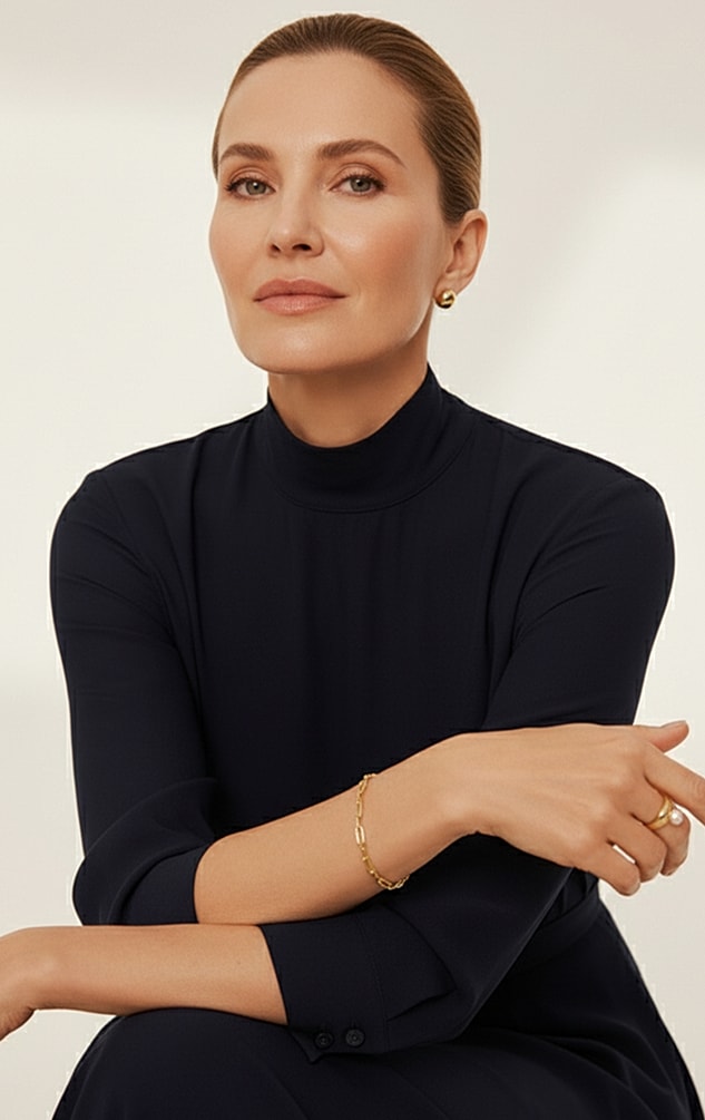 Smiling woman in a cream blazer, light background.