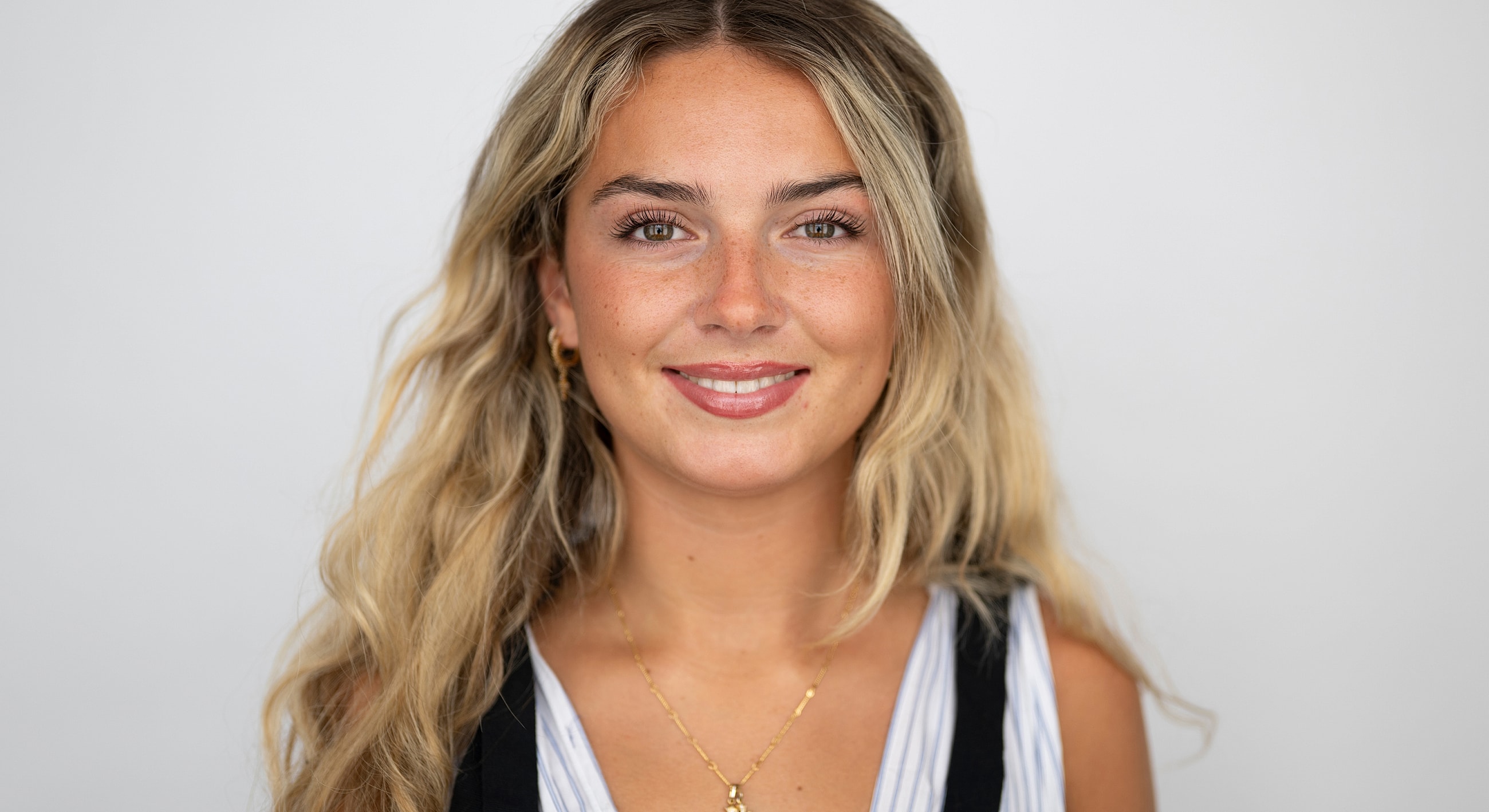 Young woman smiling with wavy blonde hair.