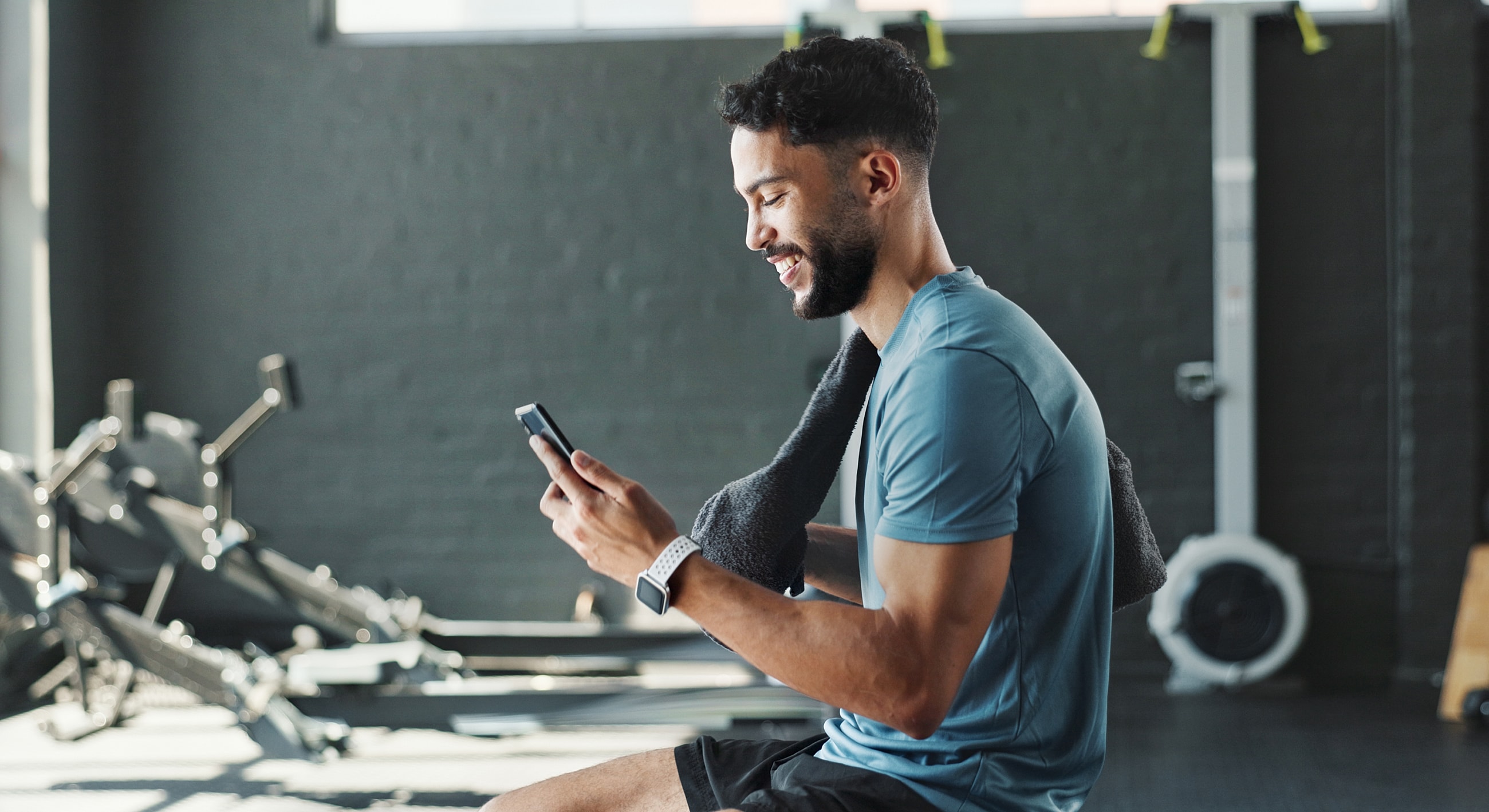 Man using phone while resting in gym.